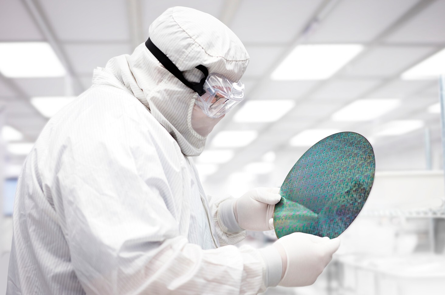 Semiconductor Engineer carefully handling a silicon wafer in a cleanroom during fabrication. Semiconductor Engineer carefully handling a silicon wafer in a cleanroom during fabrication.
